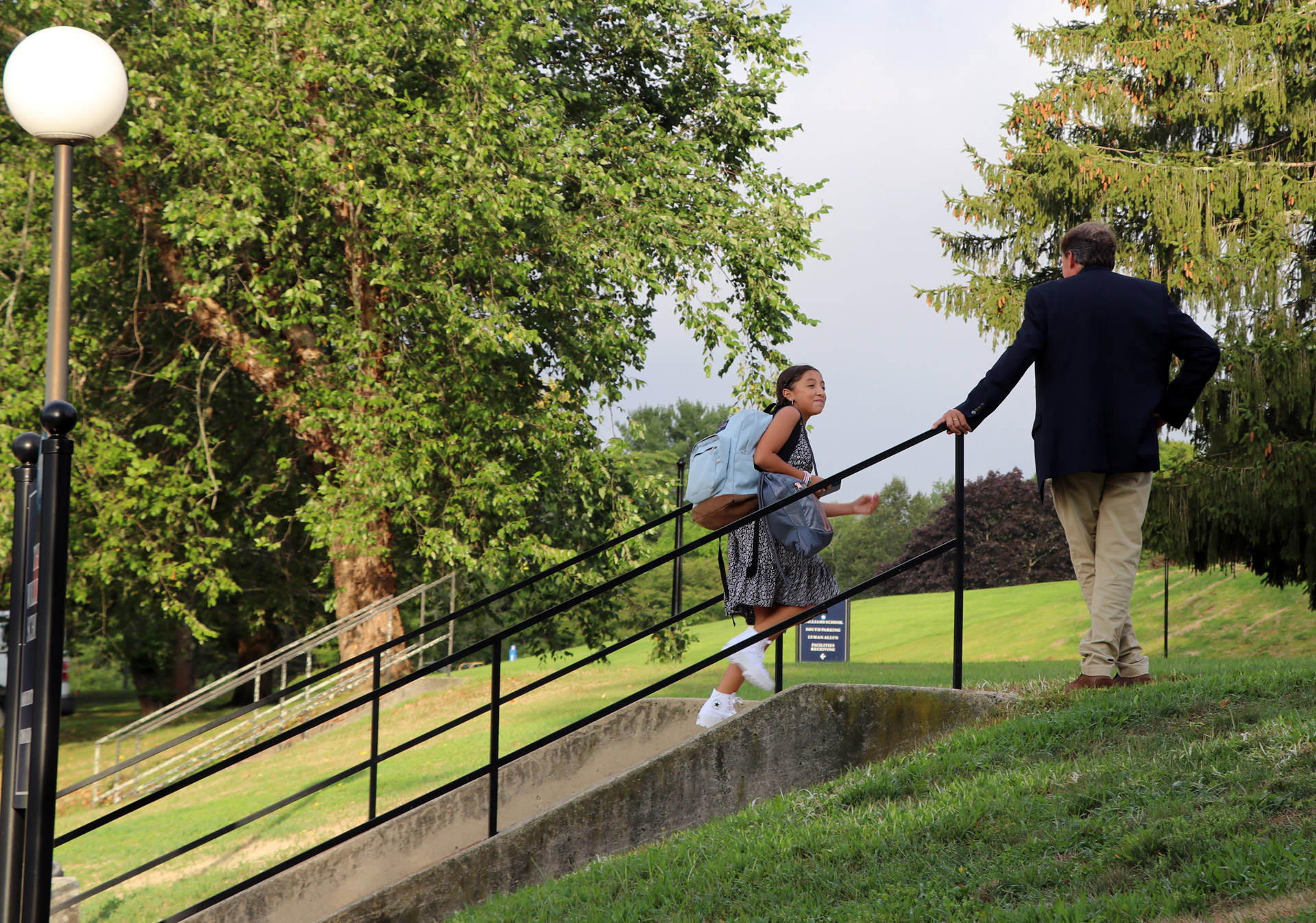 head of school greeting student walking up stairs on campus