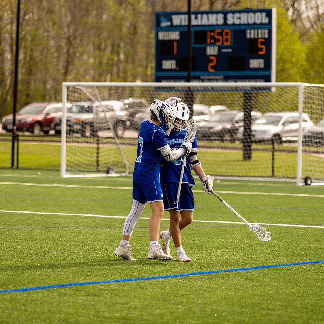 Lacrosse players supporting each other on field during game