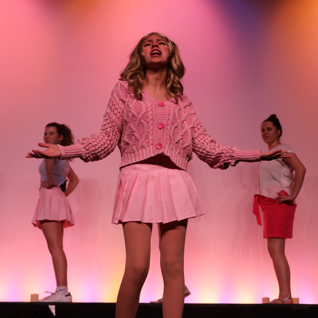 Three students in Legally Blonde production with pink lighting