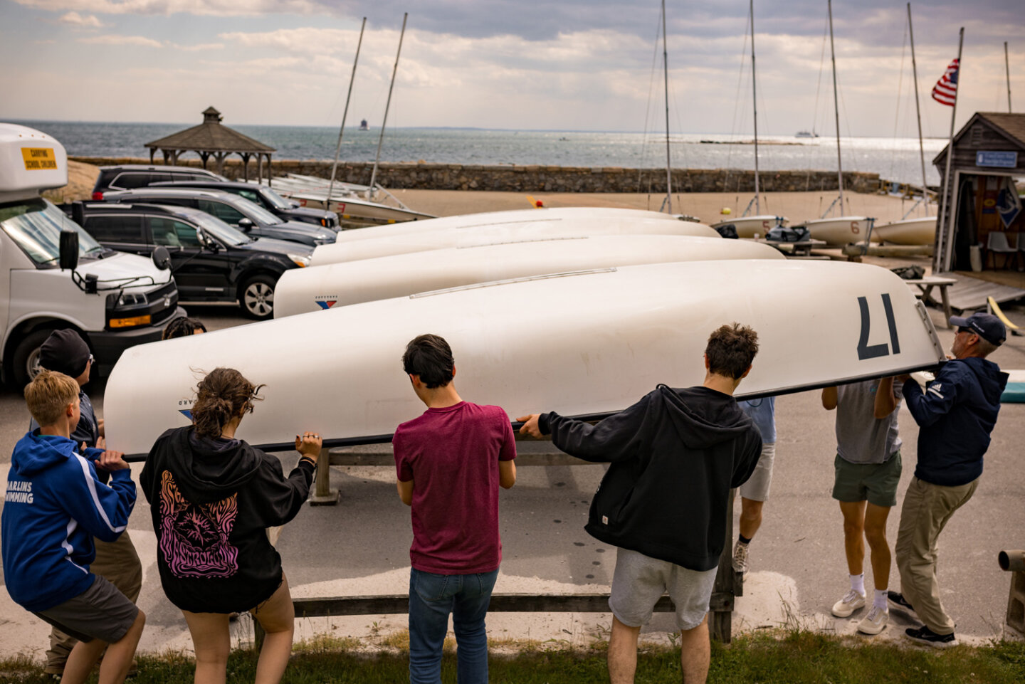 Williams sailing students help coach lift boat off of rack at the marina