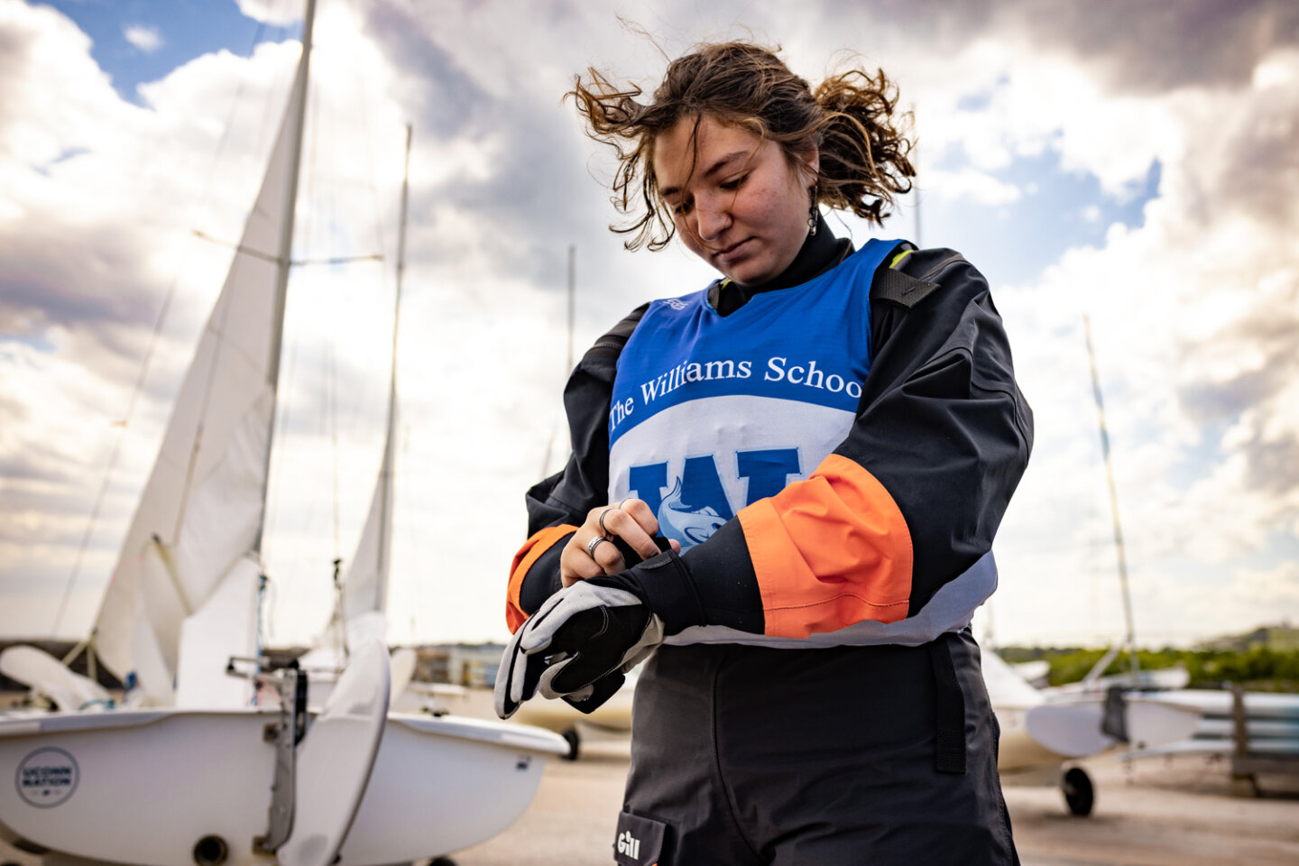 Williams school sailing student puts on their gloves on a windy day at the marina
