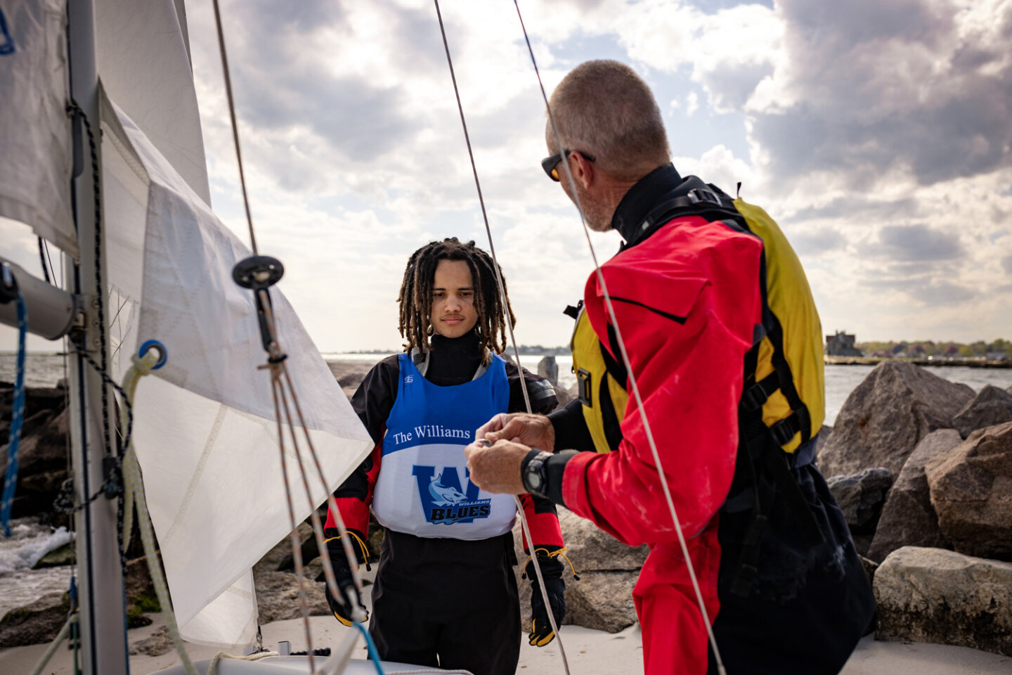 Williams school sailing student talks to sailing coach in full sailing gear next to their sailboat