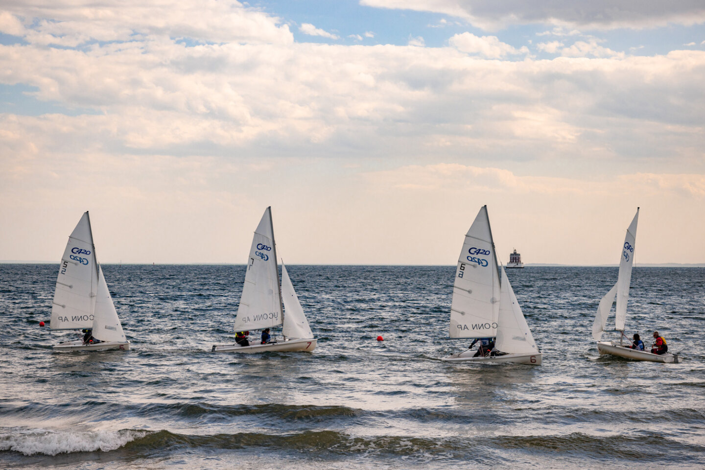 Williams School sailing students in four sailboats close to the shore
