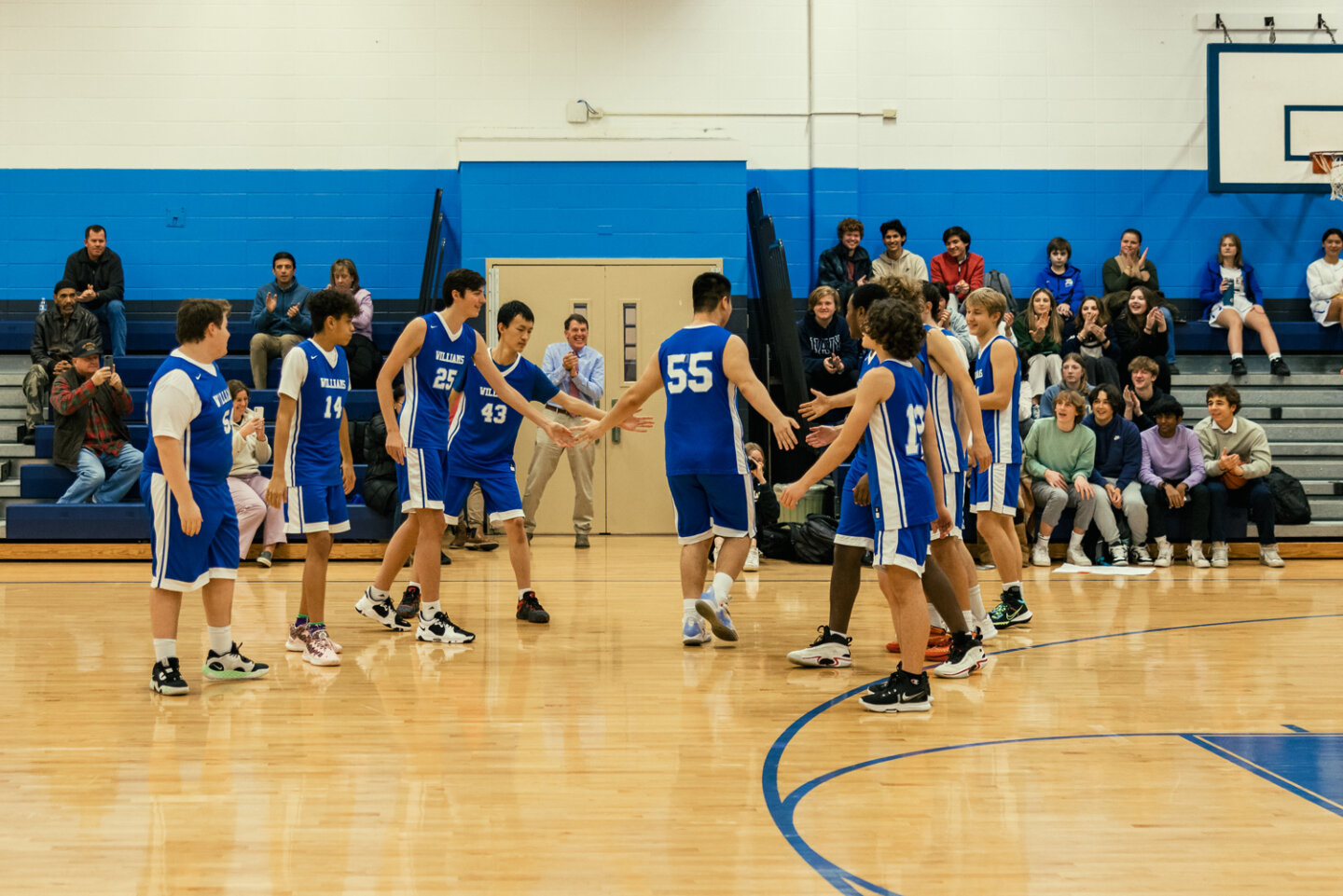 Boys basketball team cheers on player as they exit the court