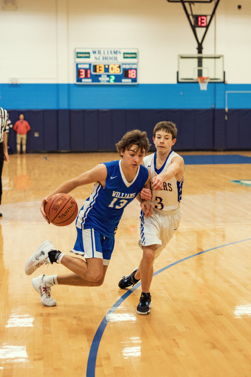 Boys basketball player dribbles toward basket opposing player guarding closely