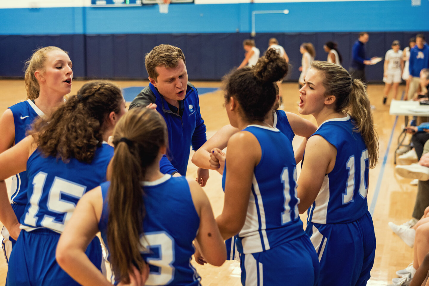 Girls basketball team huddles with coach during game