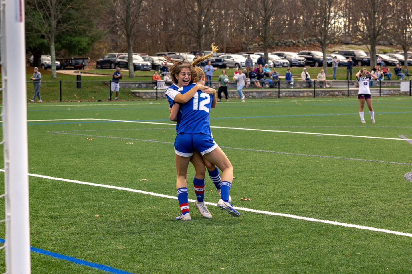 Girls soccer players hug and celebrate on the field during a game