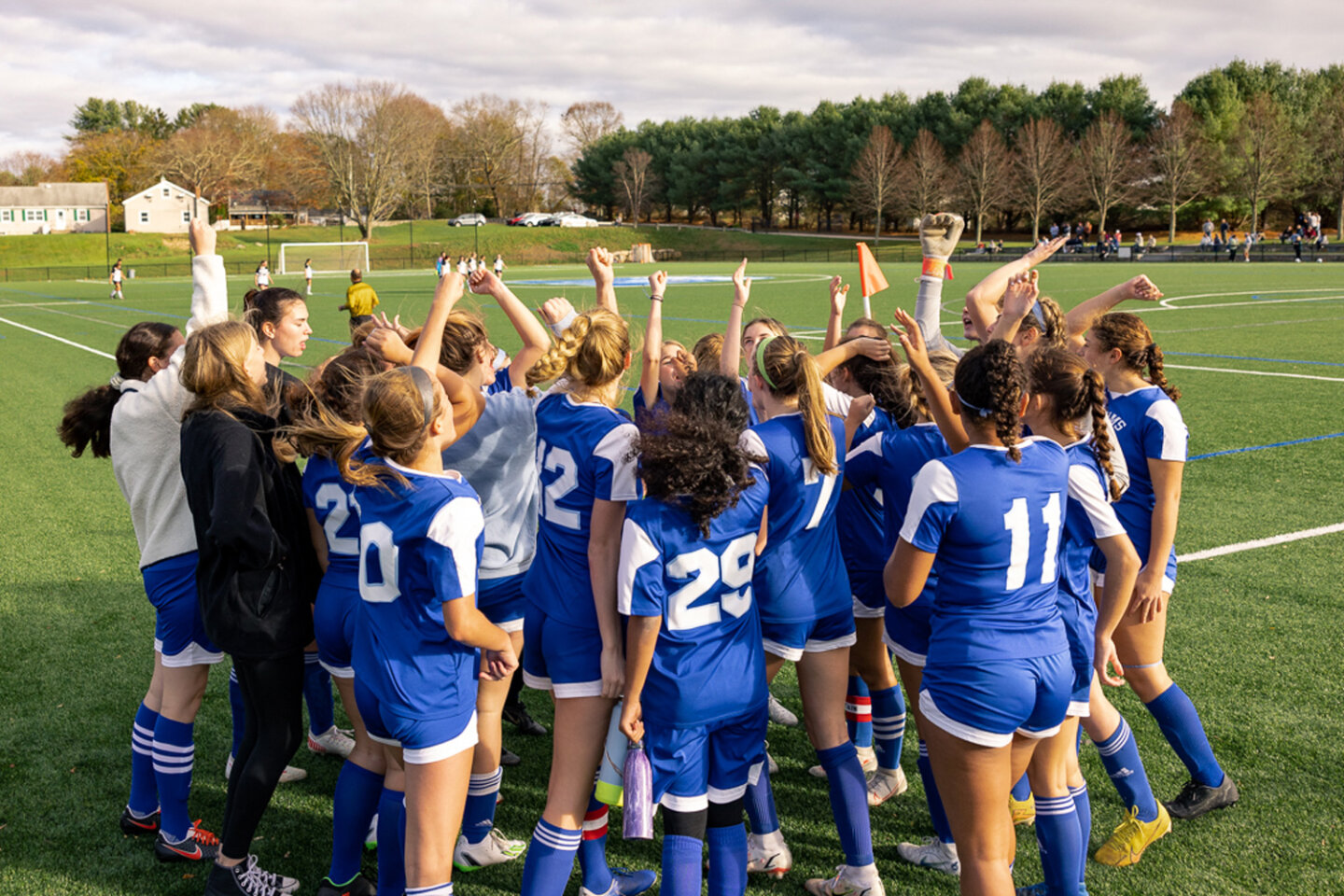Girls soccer team huddles and cheers on the soccer field