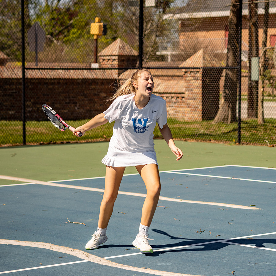 Williams School tennis player finishes a forehand swing on tennis court