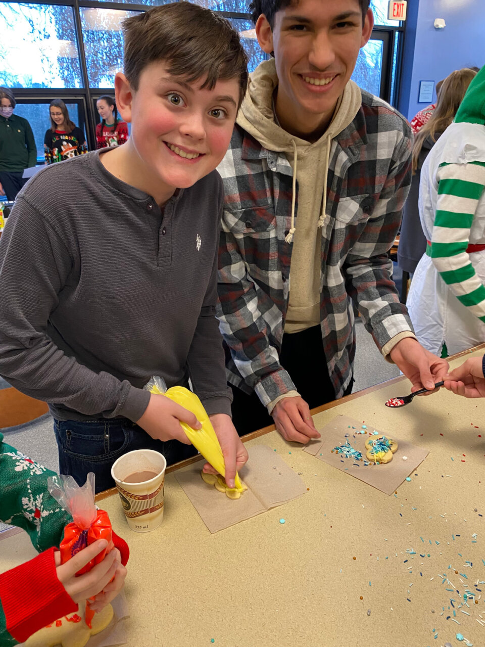 Williams School students decorating cookies with sprinkles while wearing festive clothes