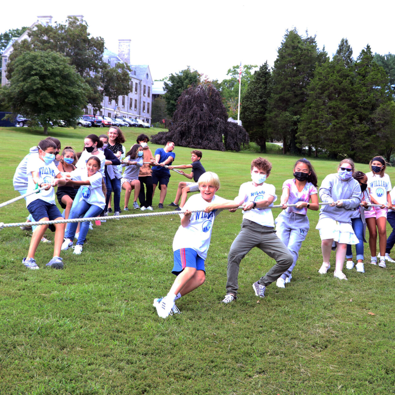 Williams School students play tug of war on grass field