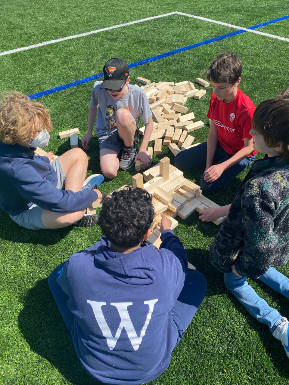 Williams School students play jenga outside on soccer field on senior day